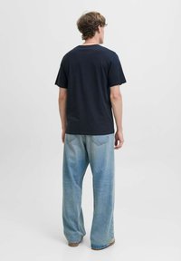 Marineblauwe katoen t-shirt met een relaxte pasvorm, korte mouwen en een ronde hals, gecombineerd met lichtblauwe, wijde jeans.