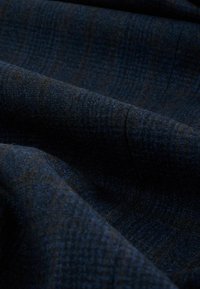 Tissu tissé de couleur bleu foncé avec des carreaux subtils marron et bleu clair. Texture douce avec un léger éclat, présentant un motif de tissage dense.