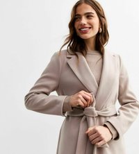 Manteau beige ceinturé avec un col châle et des manches longues. Tissu doux avec une texture lisse. Association avec un pull léger est visible.