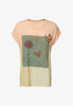 Beige t-shirt met korte mouwen en een groene patch op de voorkant met geborduurde bloem, vogel, vlinder, rode kat en gele spiraalvormige ontwerpen.