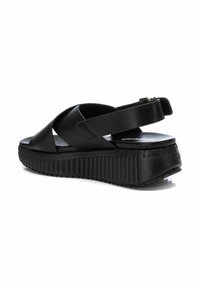 Sandalias de plataforma negras con suela texturizada, que cuentan con correas entrelazadas y una correa trasera ajustable para un ajuste seguro. Material sintético suave.