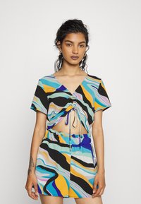 Conjunto colorido de duas peças, apresentando uma blusa de manga curta com decote em V e detalhe de cordão, combinada com uma saia-calção à correspondência. Padrões de ondas abstratos.