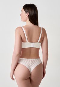 Set di reggiseno e slip in beige chiaro, realizzato in tessuto morbido, con spalline regolabili e un design trasparente a righe sul retro dello slip.