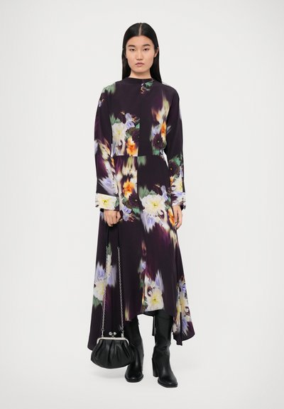 Long-sleeve purple floral dress with a high neckline, featuring vibrant colors and a flowing silhouette. Paired with black knee-high boots and a small handbag.