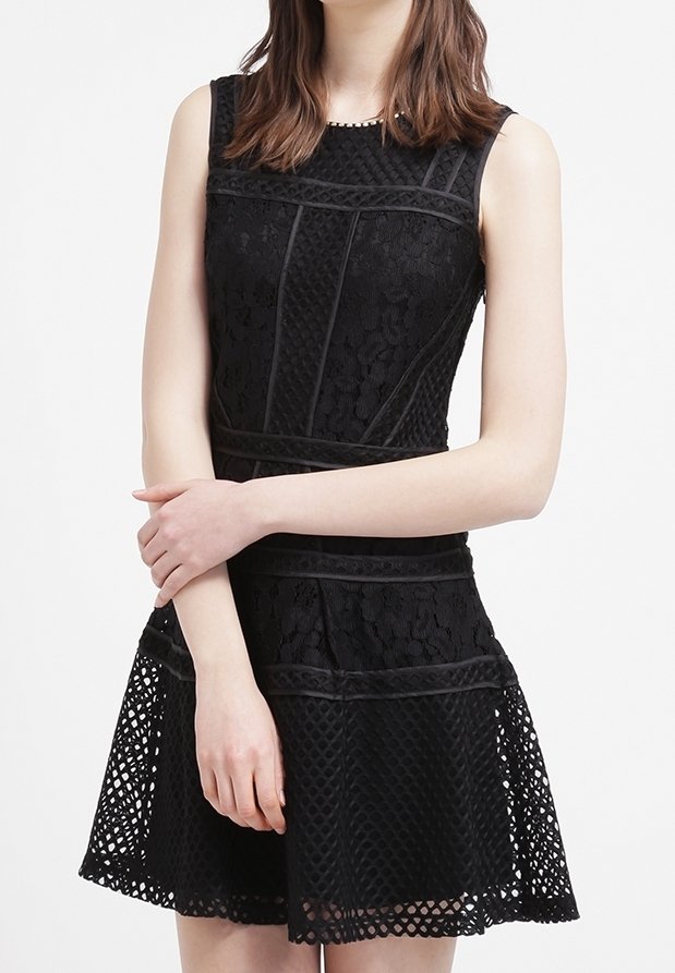 Svart spetsklänning med en figursydd bodice, ärmlös design och en utsvängd kjol med en strukturerad fåll. Vertikala sömdetaljer synliga.