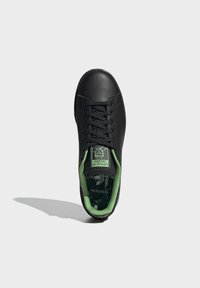 Czarny skórzany sneaker z zielonym wnętrzem, zawiązywany na sznurowadła, o fakturowanej powierzchni i logo "PRIMEGREEN" na języku.