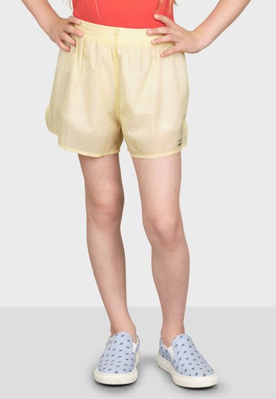 Ljusgula shorts med elastisk midja, som har en lös passform och en subtil lyster. Kombineras med blå mönstrade slip-on skor.