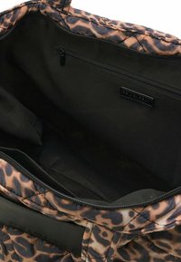 Borsa a tracolla con esterno a stampa leopardata, con interno nero e tasca con zip. Il materiale sembra morbido con un design trapuntato.
