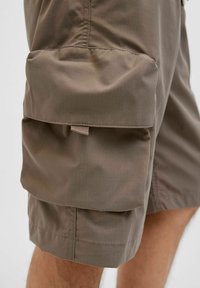 Khaki cargoshorts met twee grote voorklep zakken, gemaakt van lichtgewicht stof, met een gladde textuur en contrasterende stiksels.