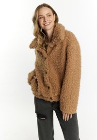 Brun, struktureret fuzzy jakke med en stor krave, knaplukning og sidelommer, parret med slidte sorte jeans.