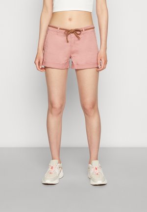 Shorts rose clair avec un cordon tressé marron, ourlet retroussé et poches latérales, associés à des chaussures de sport de couleur neutre.