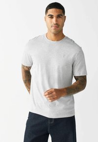 Grå kortærmet t-shirt lavet af et blødt stof, med en rund halsudskæring og en subtil broderet detalje på brystet.