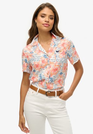 Korte mouwen, overhemd met kraag in het wit met een bloemenpatroon met roze en oranje hibiscusbloemen, blauwe accenten en een klein logo.