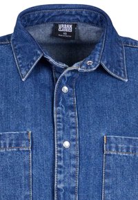 Denim overhemd in donkerblauw, met een puntige kraag, drukknoopsluiting en twee borstzakken met een subtiele vervaagde textuur.