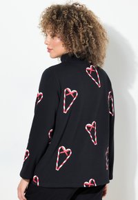 Maglietta nera a maniche lunghe con motivi a cuore a forma di bastoncino di zucchero rossi e bianchi. Realizzata in tessuto morbido con una vestibilità comoda e design a collo alto.
