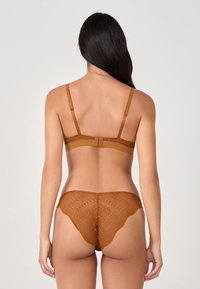 Sujetador de encaje marrón y braguitas a juego con un diseño travieso, con bordes festoneados y un patrón texturizado, que cuentan con tirantes ajustables y cierre de gancho y ojal.