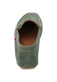 Gröna mockasnäckor med rundad tå, kontrasterande vit sömnad och en liten röd, vit och blå accent på sidan. Inuti är de bruna.