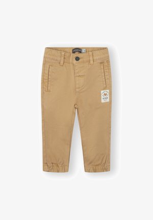 Pantalones para niño pequeños color beige con puños elásticos, bolsillos laterales, cierre de botón y un pequeño parche en el muslo derecho.