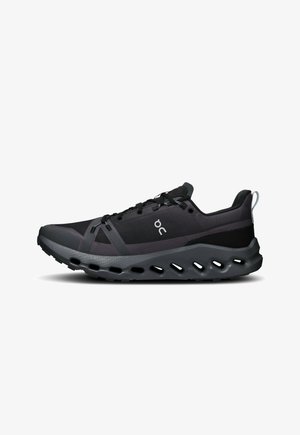 Black athletic shoe featuring mesh and synthetic materials, curved sole with cutouts, textured lacing system, and branding on the side.