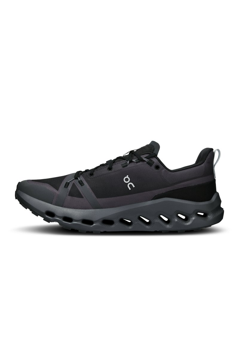 Chaussure de sport noire en mesh et matériaux synthétiques, semelle incurvée avec découpes, système de laçage texturé et marque sur le côté.