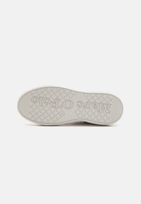 White rubber shoe sole with a textured bottom for traction. Features embossed brand name and a squared pattern across the surface.