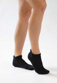Sorte ankelstrømper lavet af et blødt, strækbart materiale. Har ribbet struktur og tætsiddende pasform omkring hælen og tæerne.