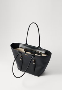 Sac fourre-tout en cuir noir avec une finition texturée, doté de deux longues poignées et d'accents dorés. L'intérieur est de couleur claire avec une poche zippée.