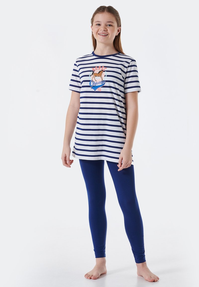 Pasiasta koszulka w białym i granatowym kolorze z graficznym wzorem na środku, zestawiona z jednolitymi, niebieskimi legginsami. Lekki materiał, luźny krój.