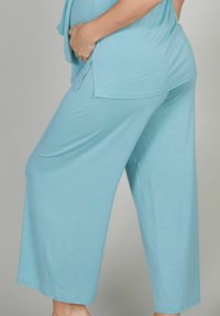 Hellblaue, weite Lounge-Hosen aus weichem, leichtem Stoff. Sie haben eine lockere Passform und eine glatte, gleichmäßige Textur.