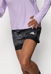Lys lilla langermet topp med strukturert stoff kombinert med svarte marmorert shorts med en tettsittende innerlag og hvite striper.