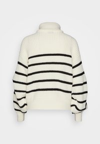 Ullgenser med høy krage, med svarte horisontale striper på en kremfarget bakgrunn, teksturert strikk og cropped passform.