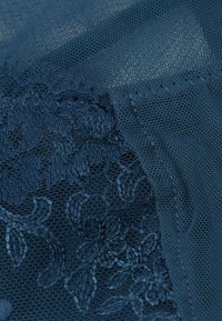 Donkerblauwe gaasstof met bloemembroiderydetails. De textuur is zacht en doorschijnend, met een verfijnd patroon en een gladde rand.