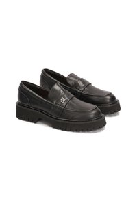 Schwarze Lederloafer mit einer dicken Gummisohle, die über genähte Details und ein kleines metallenes Emblem auf der Oberfläche verfügen.