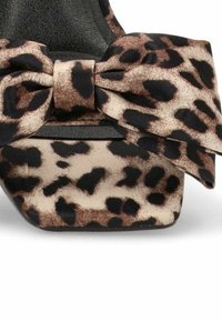 Zapato de tacón alto con estampado de leopardo y un gran detalle de lazo. El exterior presenta una suave tela texturizada con una suela negra. Forma de punta cuadrada.