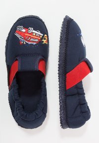 Marineblauwe slipper met rode accenten, bovenwerk van stof met een geborduurd ontwerp van een rode brandweerwagen, en een gestructureerde rubberen zool voor grip.