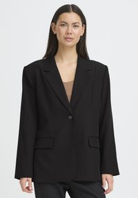 Blazer noir cintré avec une fermeture à un bouton, de larges revers et deux poches avant ; fabriqué en tissu structuré à texture lisse.