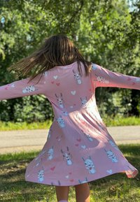 Vaaleanpunainen mekko pitkillä hihoilla, jossa on painatus pupuista ja sydämistä. A-linjainen malli, kevyt kangas, sopii lämpimään säähän.