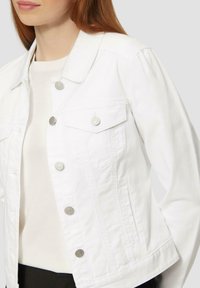 Witte denimjack met zilveren knopen, klepzakken en een klassieke kraag. Gladde textuur met een aansluitende pasvorm.