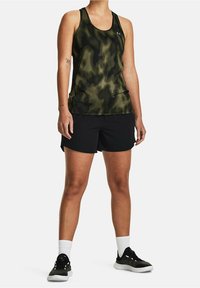 Tarnmuster-grünes Tanktop mit gerippter Textur, kombiniert mit schwarzen Sportshorts und schwarzen Schuhen, die weiße Socken tragen.