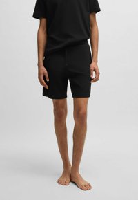 Shorts en mélange de coton noir avec une taille élastique et des poches latérales ; associés à un haut à manches courtes texturé assorti.
