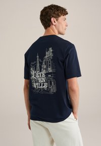 Navyblaue T-Shirt aus Baumwolle mit lockerer Passform. Es verfügt über ein weißes Linienkunst-Design von Stadtlandschaften und den Text "ETE EN VILLE" auf der Rückseite.