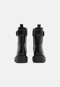 Bottes noires en cuir à finition lisse, fermeture éclair et sangle réglable à l'arrière. Semelles en caoutchouc épaisses pour plus de durabilité.