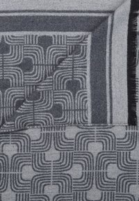 Écharpe en mélange de laine avec un motif géométrique de courbes entrelacées dans des nuances de gris, bordée d'une bande plus foncée et finie avec des franges.