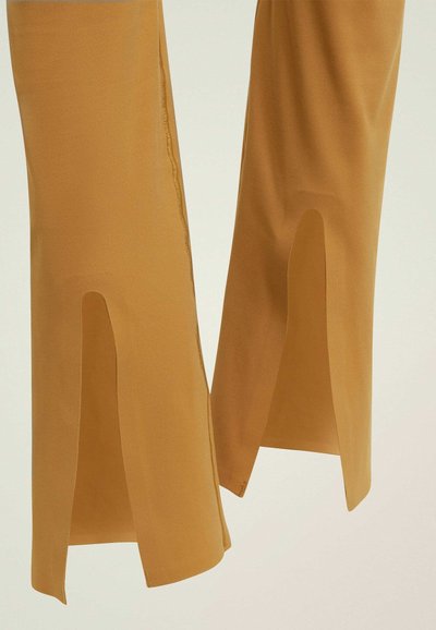 Geel, hoogopgetrokken broek met gespleten zomen, gemaakt van een gladde stof. Heeft nette stiksels en een op maat gemaakte pasvorm met een enkellange stijl.