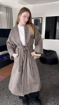 Bruine badjas met visgraatpatroon, brede mouwen en een tailleband, voorzien van zakken aan de voorkant en een gestructureerde afwerking, gedragen over een wit overhemd.