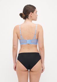 Light blue lace bra with adjustable straps and a hook-and-eye closure, paired with black high-waisted panties featuring a scalloped edge.