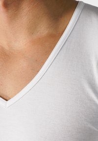 T-shirt en coton blanc avec un design à col en V. Texture douce, couture visible le long de l'encolure et de la zone des épaules. Style minimaliste.