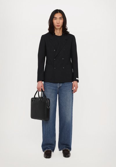 Black double-breasted blazer, wide-leg blue jeans, black leather bag, and brown shoes. Solid colors, modern cut, and tailored design.