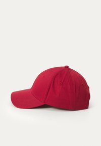 Red baseball cap made of cotton, featuring a curved visor, stitched accents, and ventilation holes on the sides.