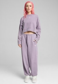 Sudadera corta morada con mangas largas y conjunto de pantalones de chándal. Tejido suave con cinturilla elástica y detalle de logo en el muslo izquierdo.